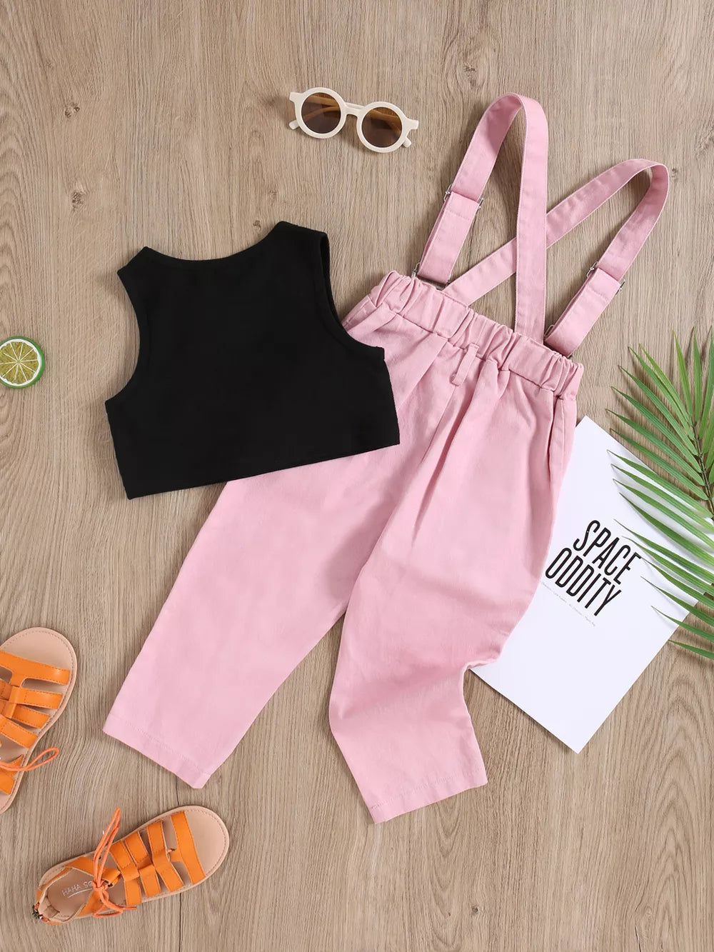 Black graphic tank top with pink distressed overalls for baby girls.