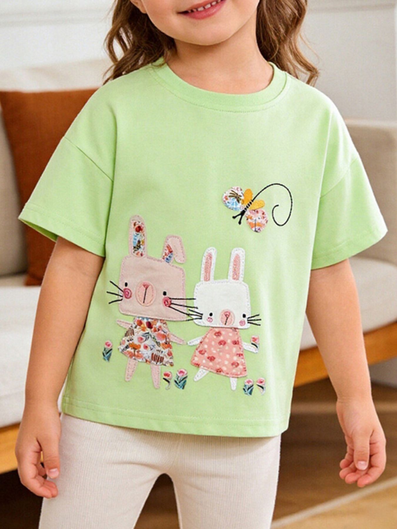 Light green short sleeve tee with appliqued bunnies and butterfly, floral dress detail.