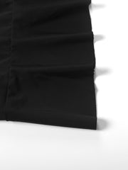 Black asymmetrical ruched mini dress detail showing fabric texture and ruching.