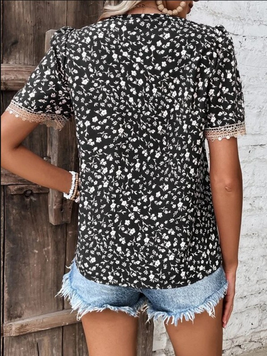 Black floral print blouse with lace trim short sleeves and V-neck.