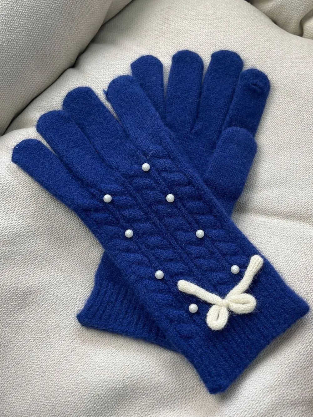 Dark Blue cable knit gloves with pearl embellishments and a white bow detail.