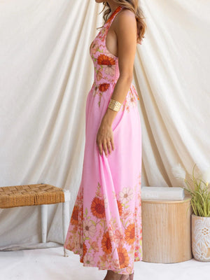 Pink floral halter neck maxi dress with a flowing skirt and side pocket detail.