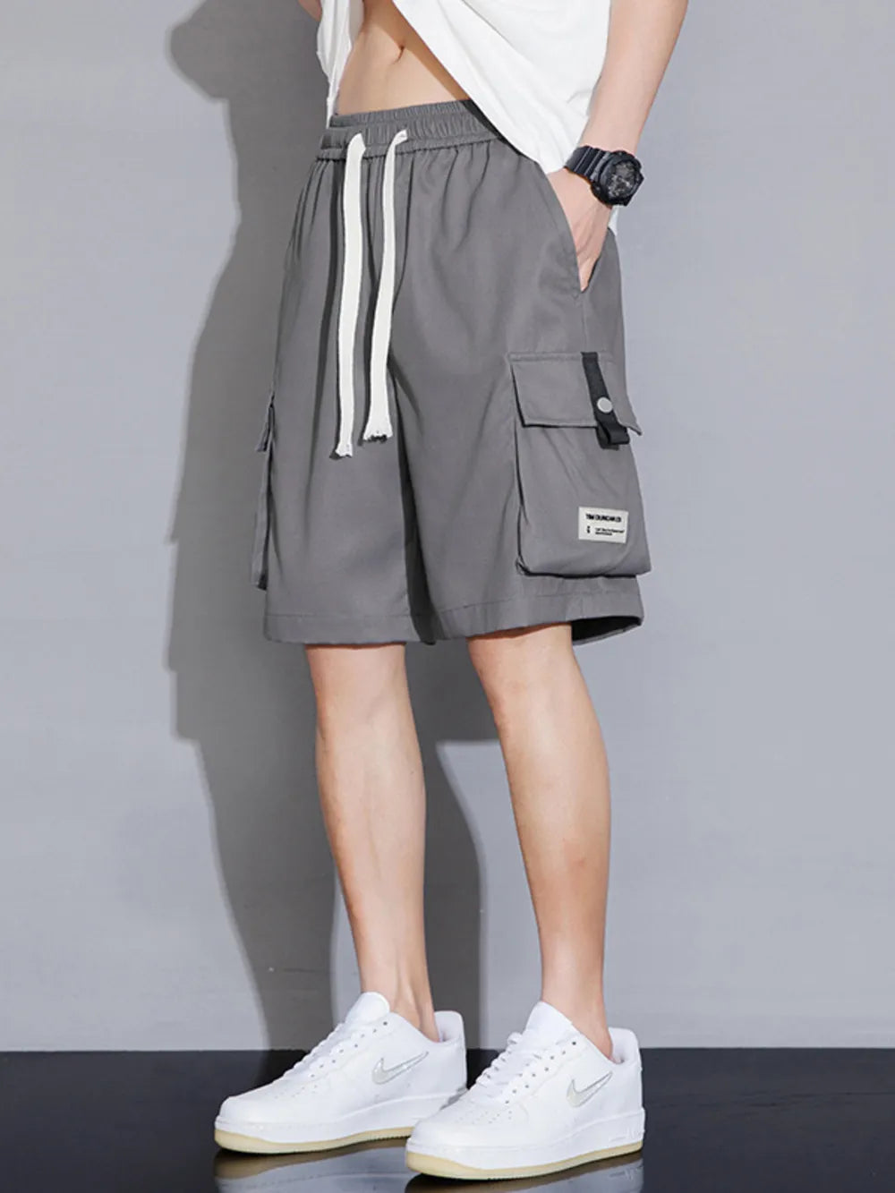 Grey cargo shorts with drawstring waist and multiple pockets, styled casually.