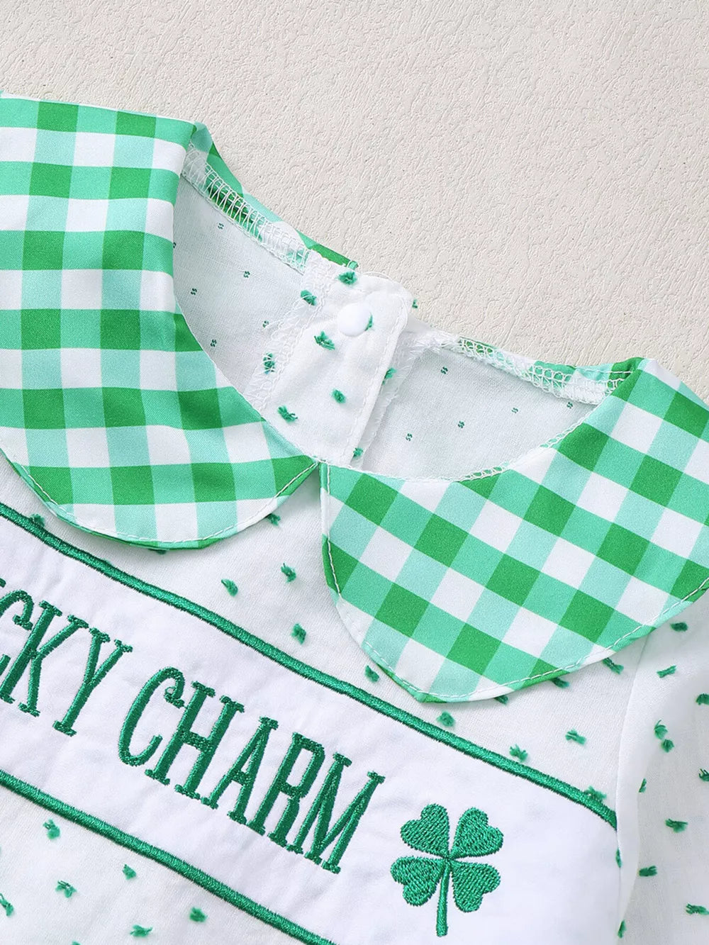 Baby set with green gingham collar, white fabric, embroidered "Lucky Charm" text and shamrock.