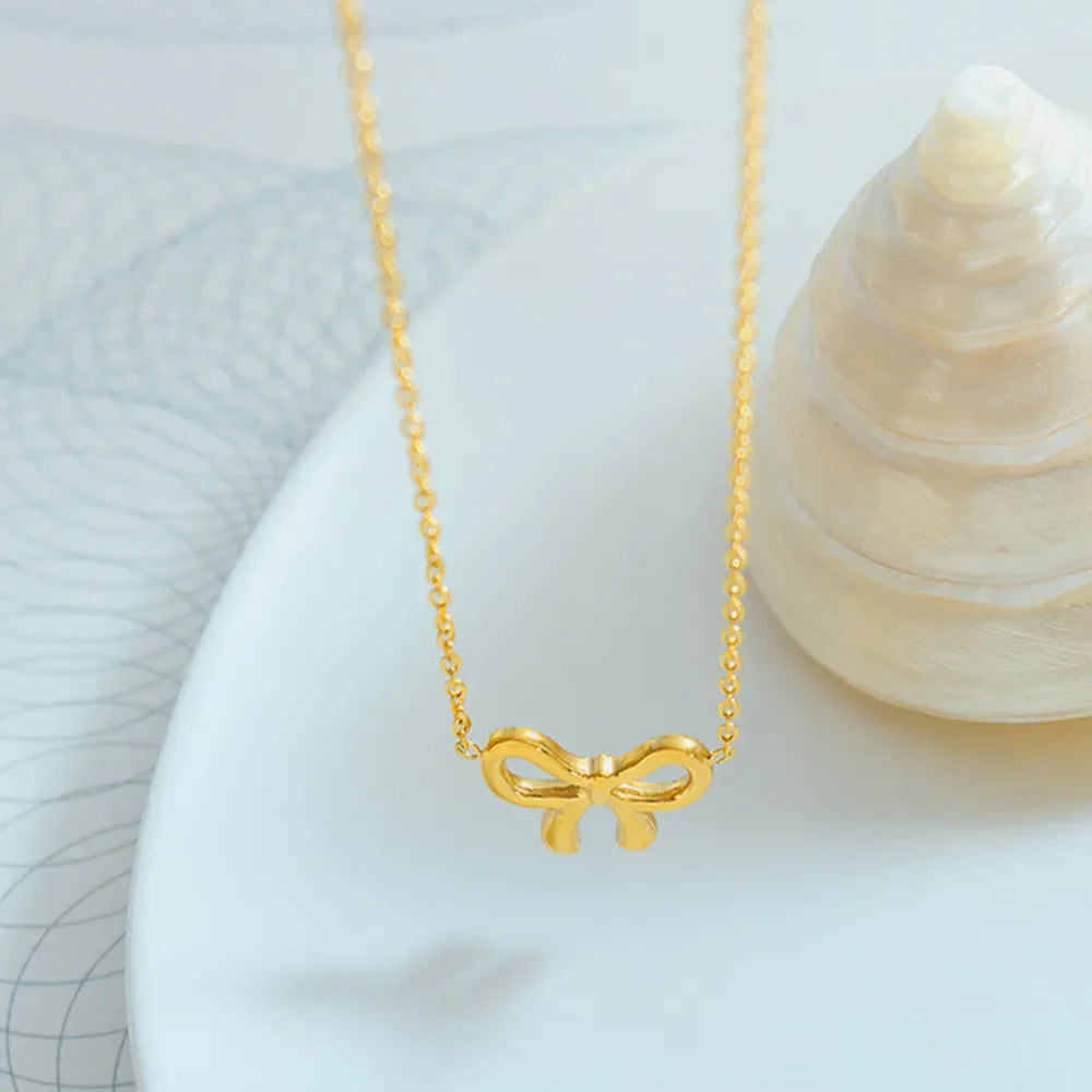 Delicate gold bow pendant necklace on a fine chain.