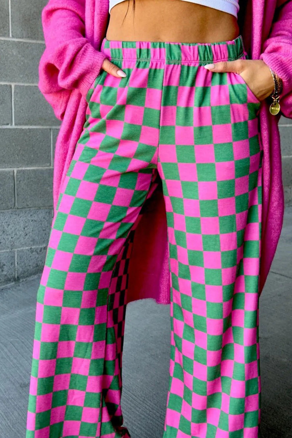 Checkerboard palazzo trousers in pink and green with elastic waist and wide leg.