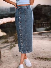 Button-front denim midi skirt in a medium blue wash with a slit hem.