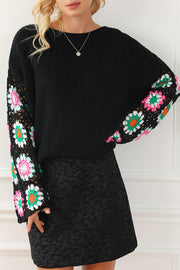 Black knit pullover sweater with colorful crochet granny square sleeves.