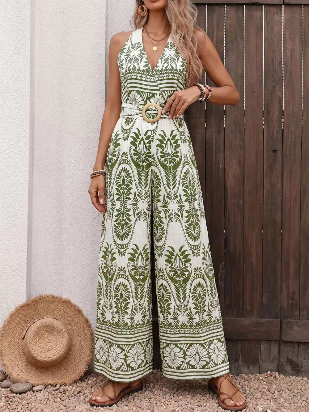 Botanical print halter neck jumpsuit with wide legs and a wooden buckle belt.