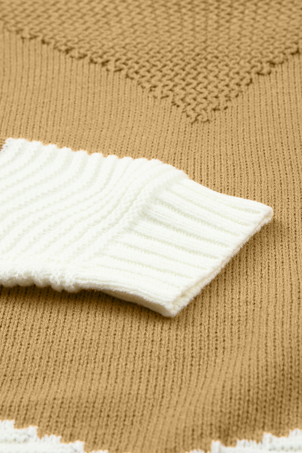 Tan knit sweater with white ribbed sleeve detail and geometric pattern.