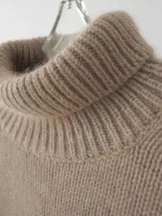 Beige acrylic knit turtleneck sweater with ribbed collar and dropped shoulders detail.