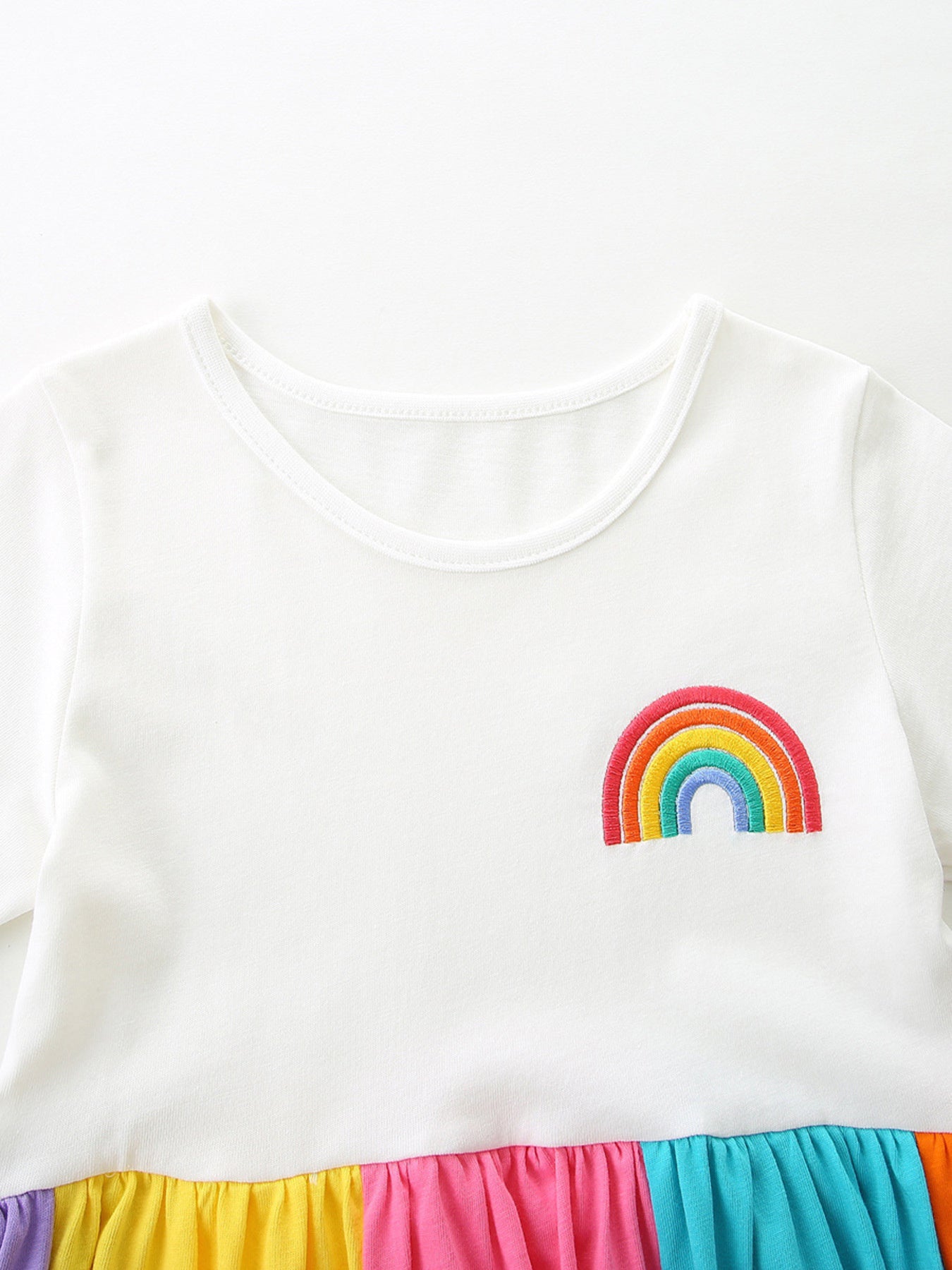White cotton toddler dress with embroidered rainbow and colorful tiered skirt.