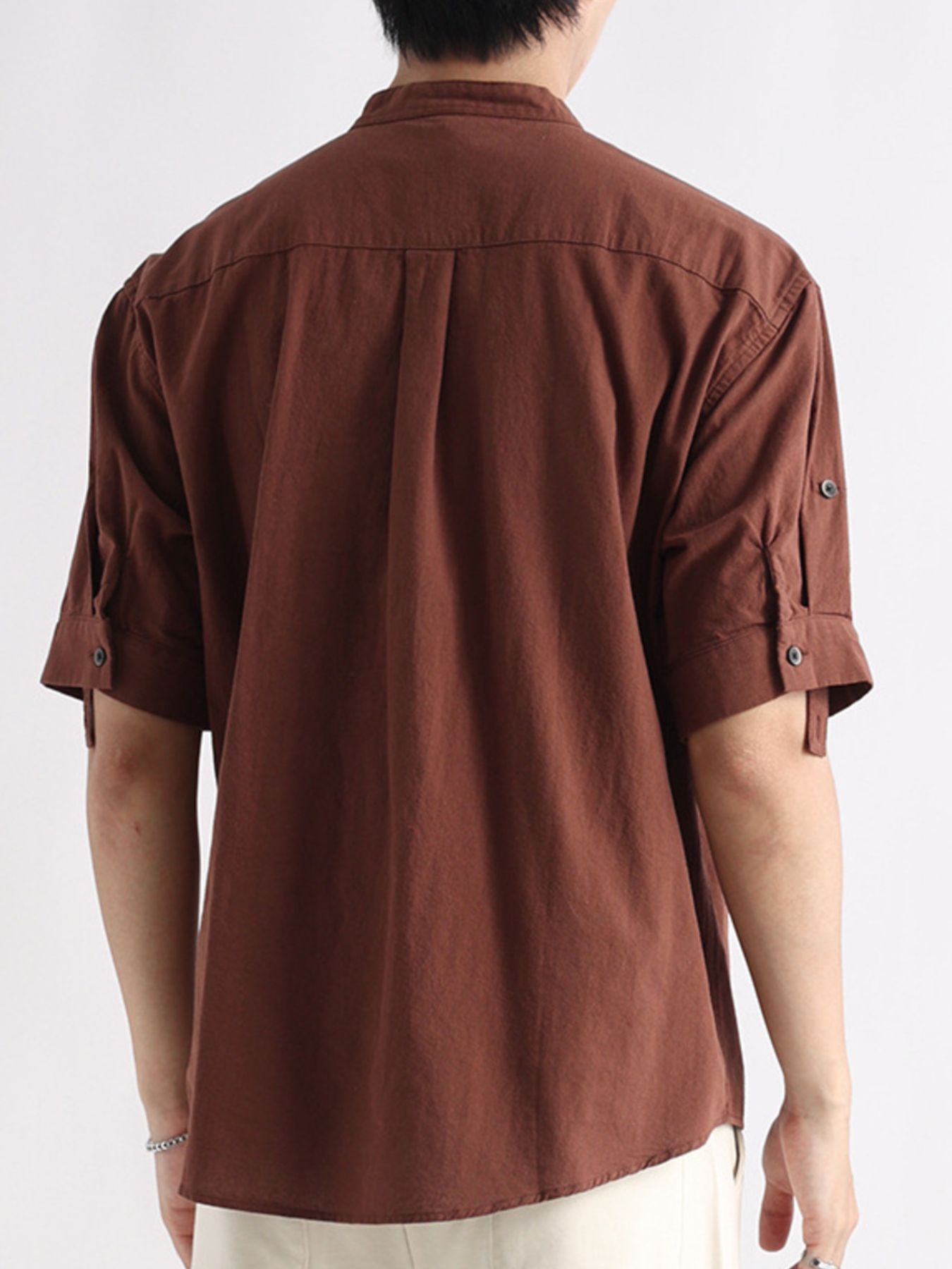 Brown band collar button-down blouse with roll-tab sleeves and back pleats.