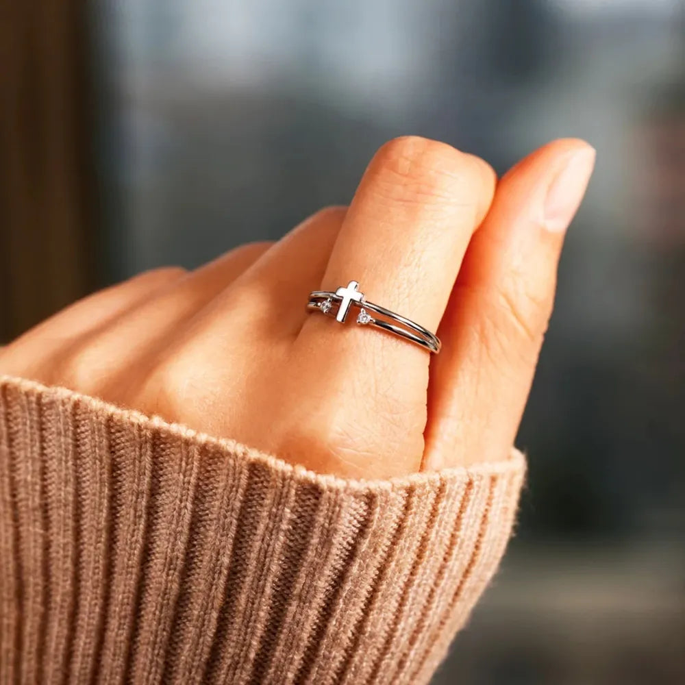 Silver double band cross ring with crystals on a hand.