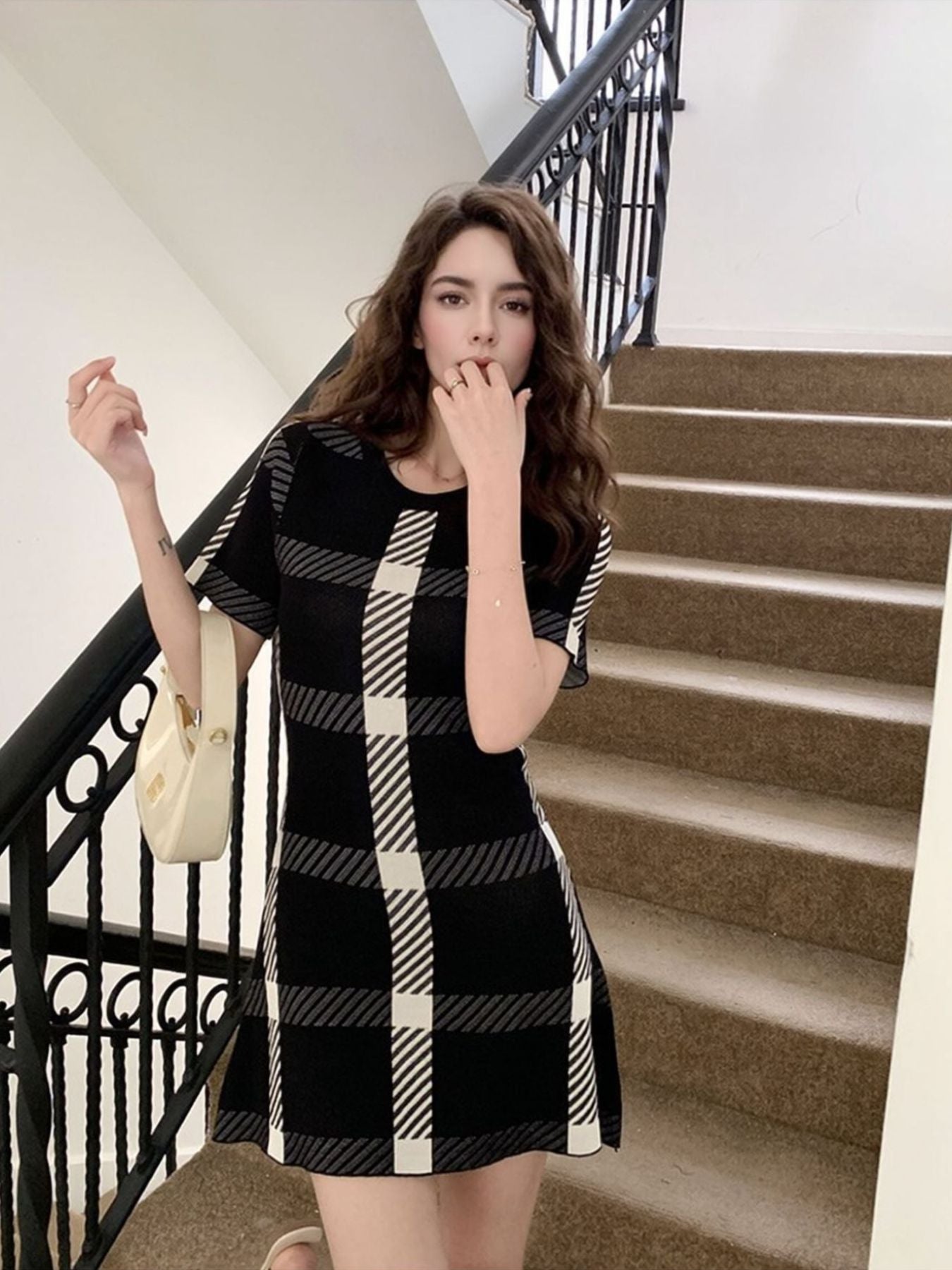 Black and white plaid mini dress with short sleeves and a crew neck, styled with a cream handbag.