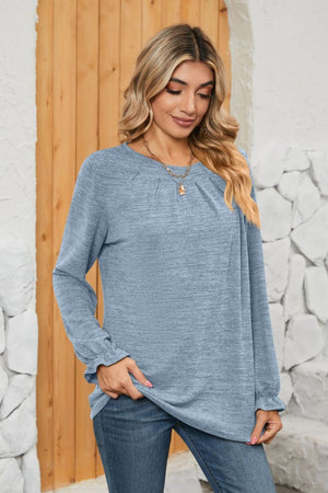 Light blue knit top with pleated yoke and ruffled cuffs, long sleeves.