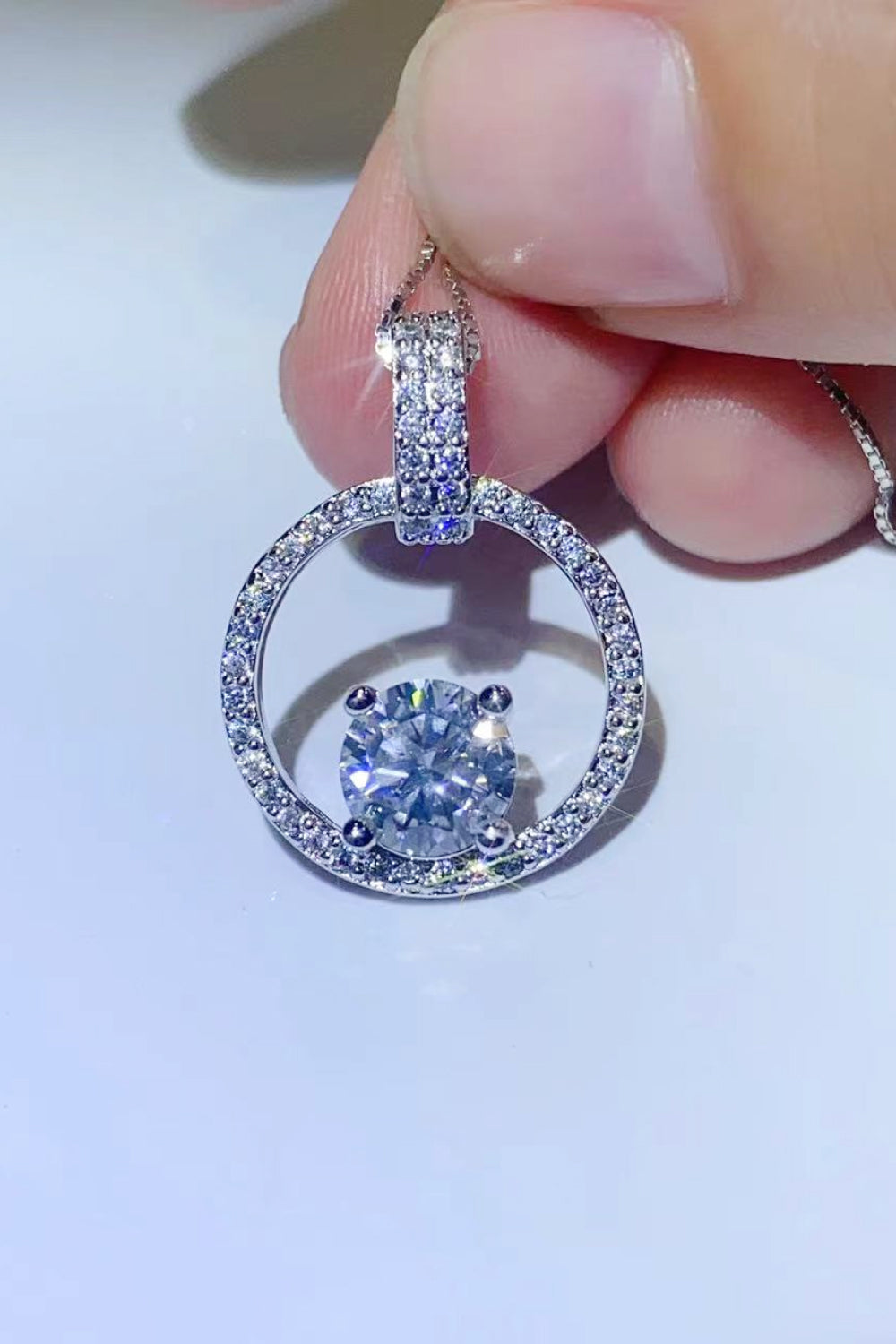 Silver halo moissanite circle pendant necklace with pave diamond bail and center stone.