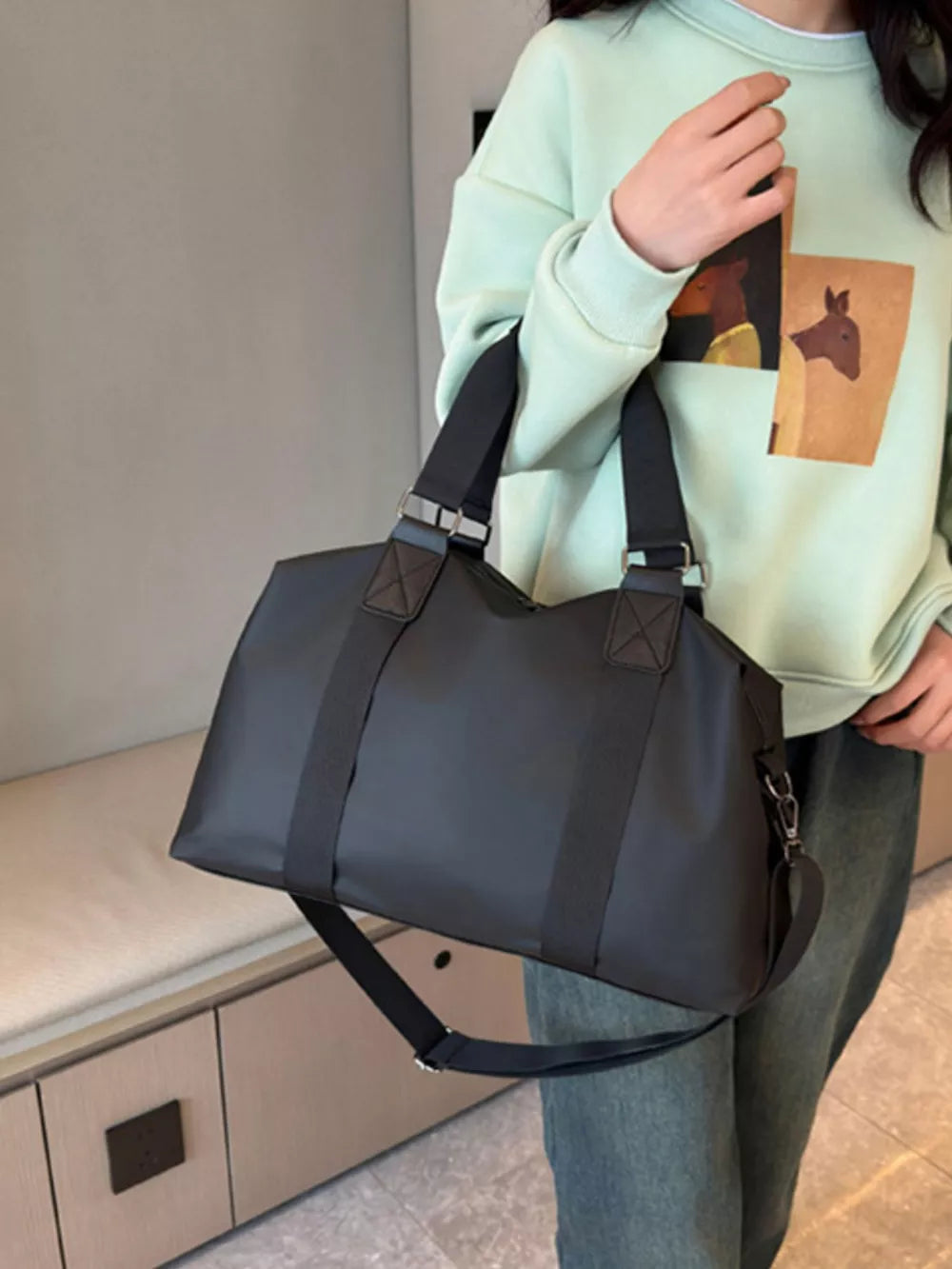 Sleek black Oxford cloth travel duffel bag with dual handles and adjustable shoulder strap.