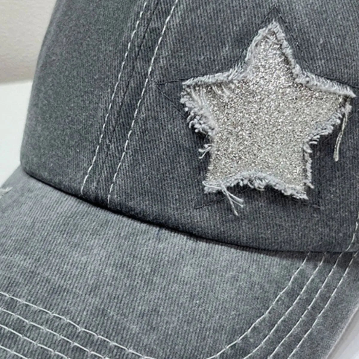 Gray baseball cap with distressed glitter star detail and white stitching.