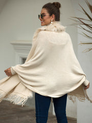 Ivory knit cape with faux fur trim and fringe detailing.