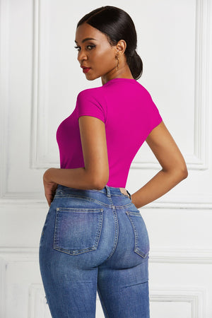 Sculpted crew neck bodysuit in hot pink with short sleeves, styled with denim jeans.