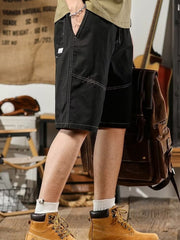 Men's black relaxed fit drawstring shorts with contrast stitching and cargo style pockets.