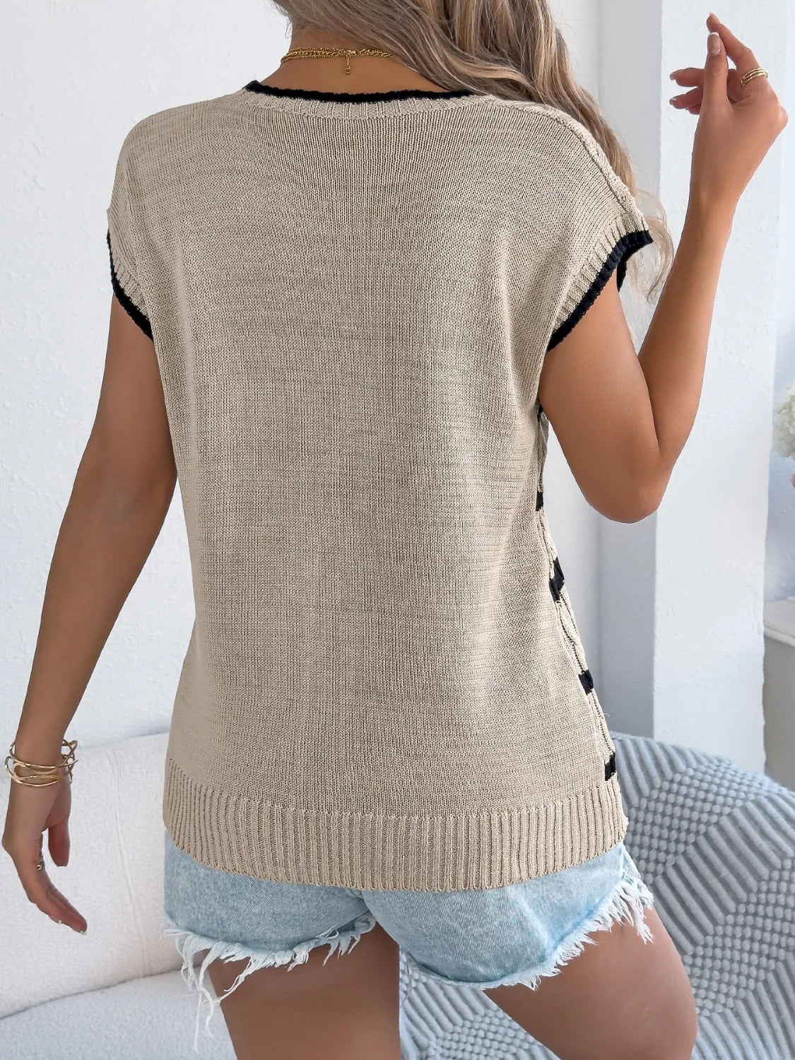 Khaki cable knit sleeveless sweater with black trim and side detail.