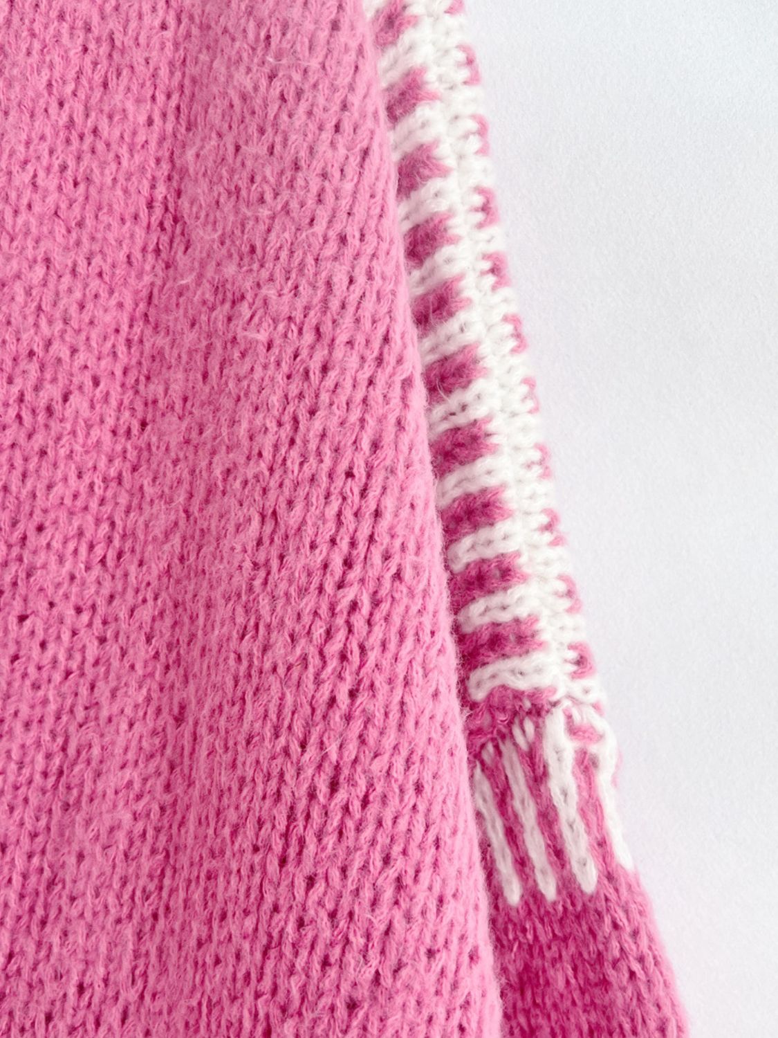 Pink knit cardigan with contrast white and pink striped sleeves and hem detail.