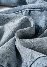 Cuffed hem washed denim trousers in medium acid wash with visible stitching detail.