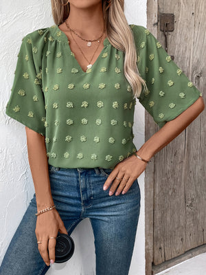 Moss Swiss dot blouse with v-neck and short sleeves, styled with jeans.