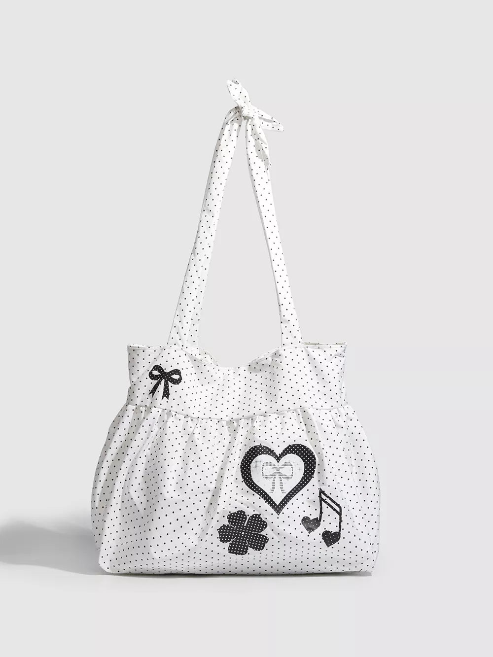 White polka dot canvas shoulder bag with heart, bow, clover, and music note appliqués.