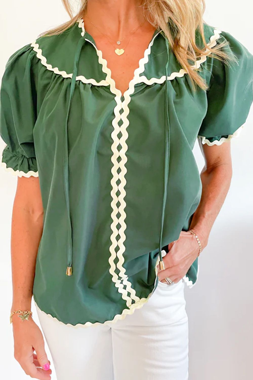 Moss green blouse with puff sleeves, tie neck, and scalloped trim.