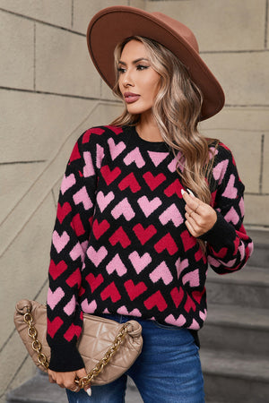 Black knit sweater with allover pink and red heart pattern, crewneck, long sleeves.