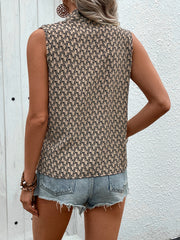 Tan geometric print draped sleeveless blouse with a mock neck, paired with denim shorts.
