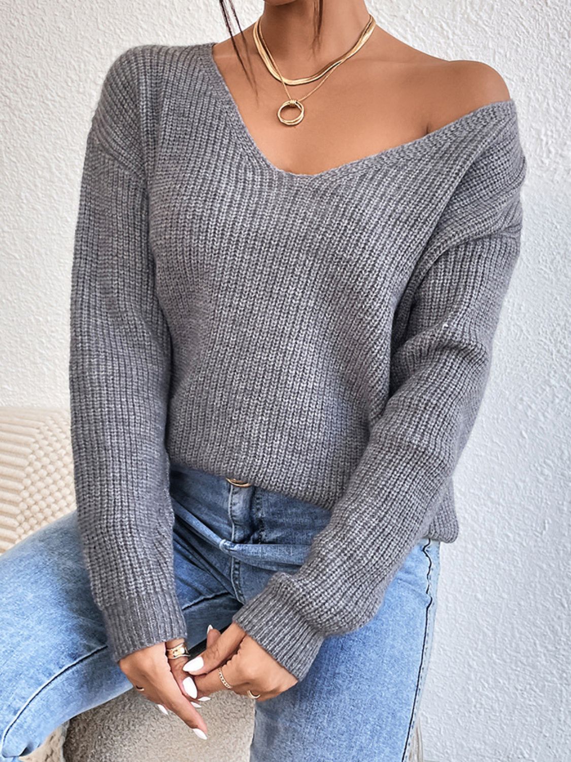 Gray ribbed knit sweater with V-neck and long sleeves, styled with jeans.