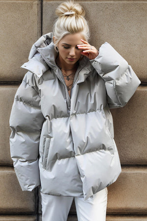 Light gray oversized puffer jacket with hood and zipper detail.