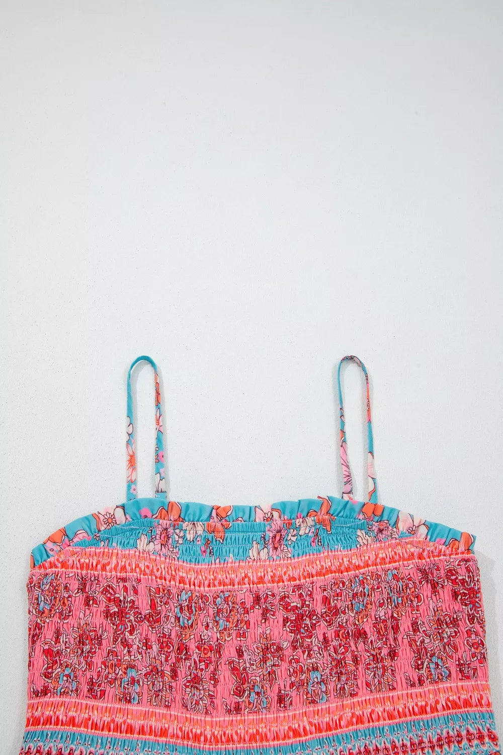 Smocked floral maxi dress with spaghetti straps and a ruffled neckline in pink, orange, and blue.