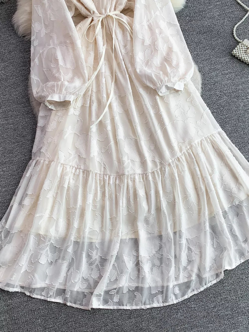 Embroidered tie-waist dress in ivory with sheer floral overlay and tiered skirt.