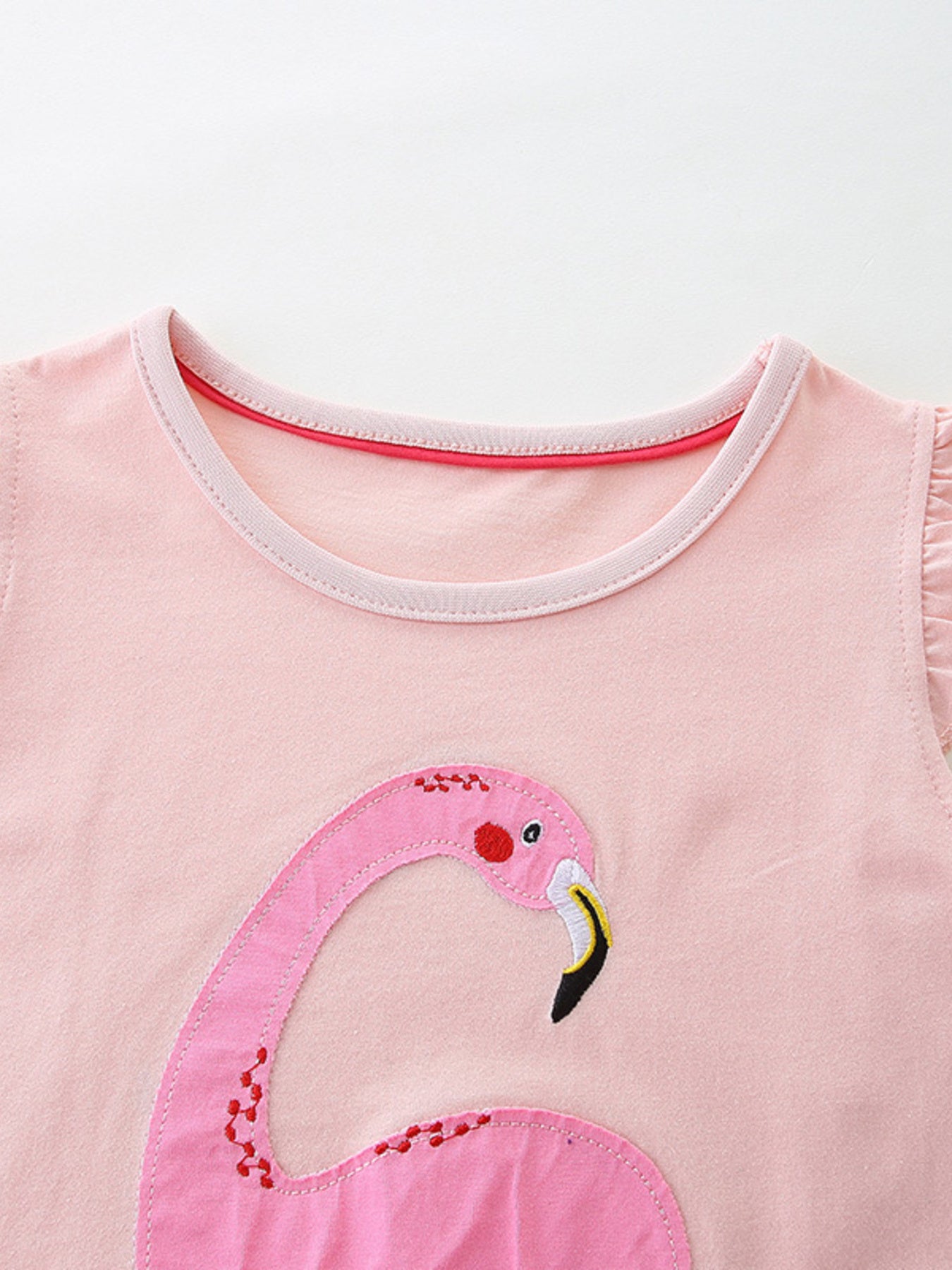 Pink cotton baby dress with flamingo appliqué and ruffled sleeves.