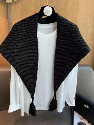 Black chunky knit scarf accessory with tassels, styled over a white shirt.