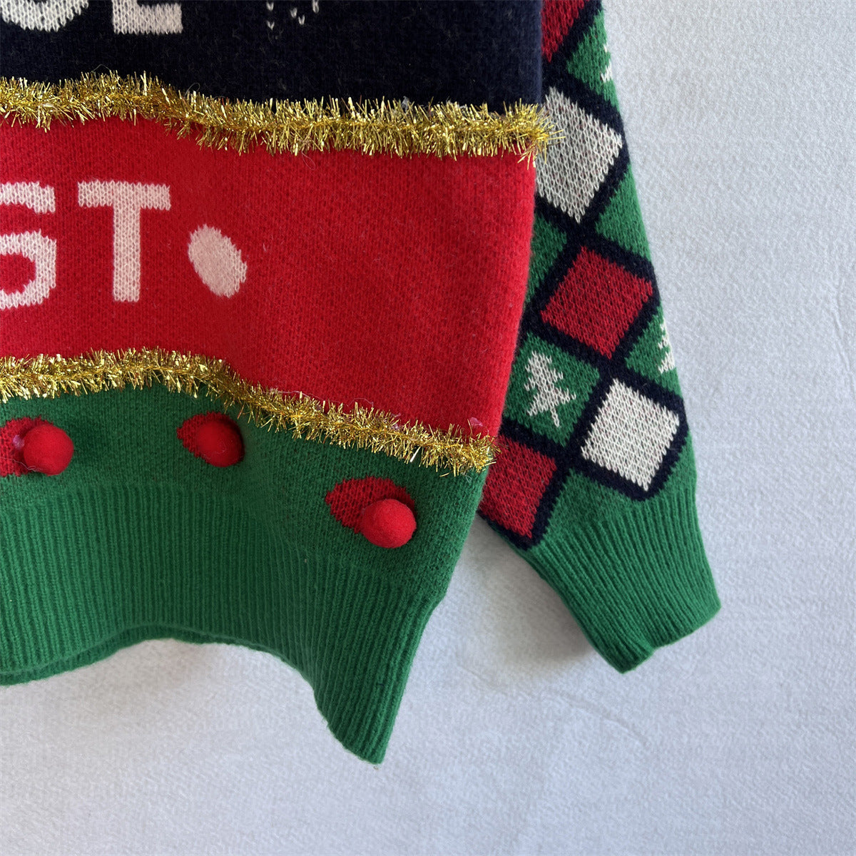 Green acrylic crewneck sweater with red, white, and gold holiday graphic details and argyle sleeves.