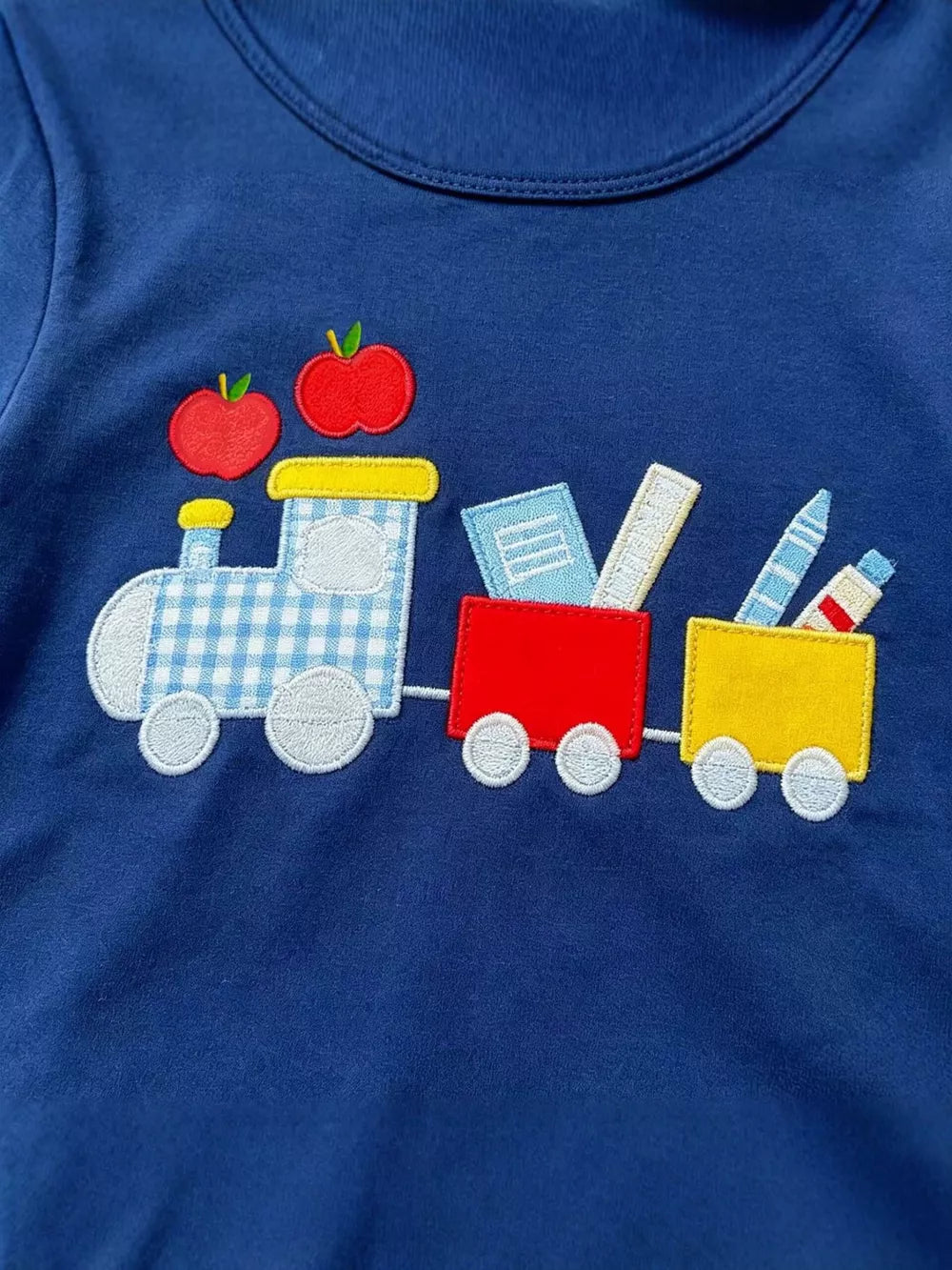 Navy blue cotton tee with embroidered train, apples, books, and crayons.