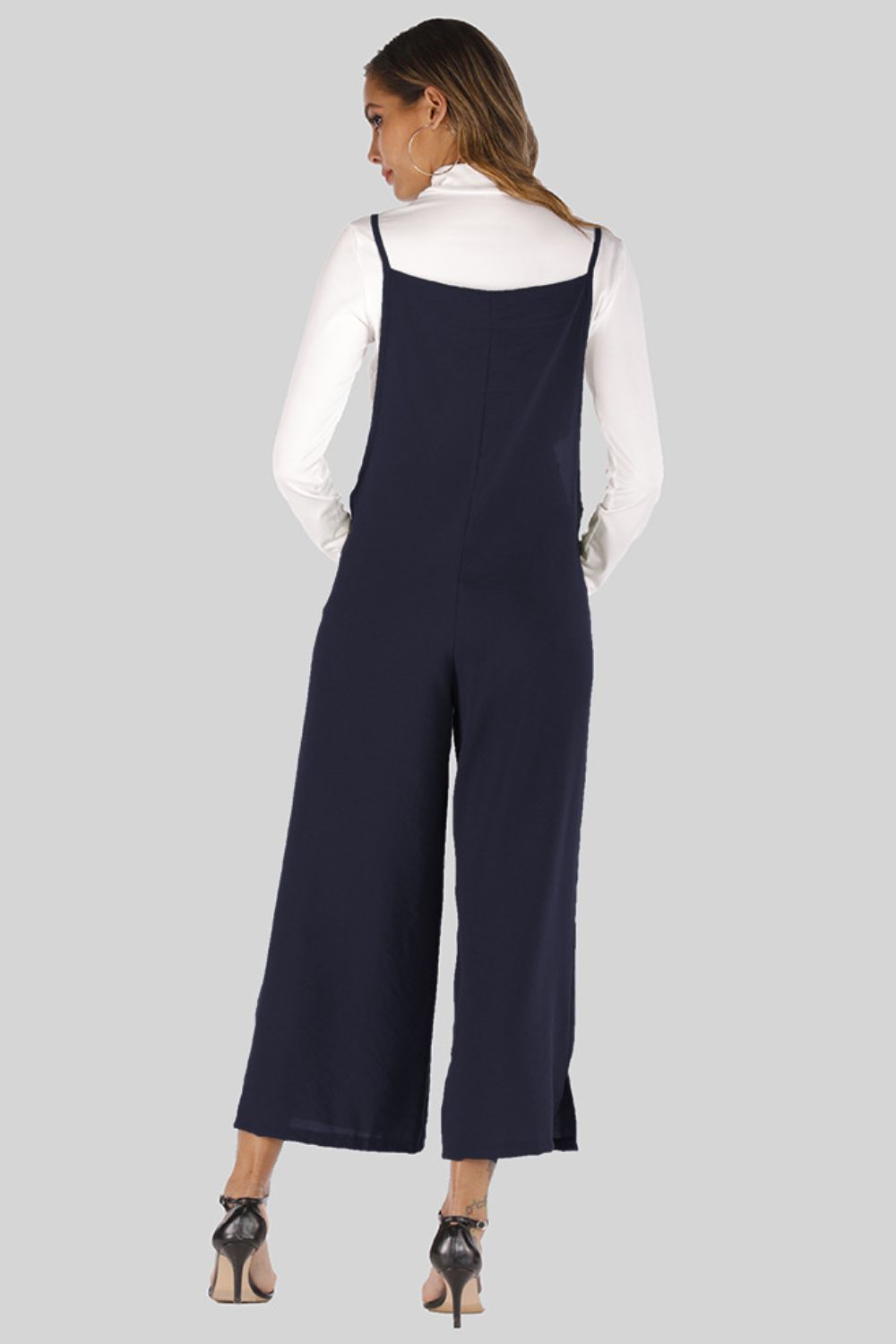 Dark Navy culotte overalls with slender straps, wide legs, and a white turtleneck top.