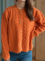 Orange cable knit cardigan with puff sleeves and gold buttons.