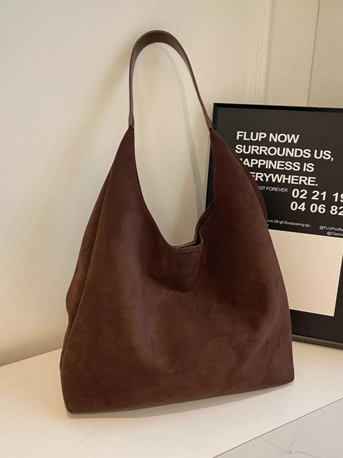 Brown suede hobo bag with a single strap and slouchy silhouette