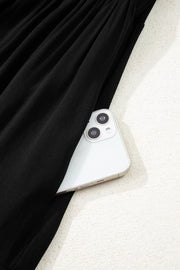 Black tiered maxi dress with hidden side pocket holding a smartphone.