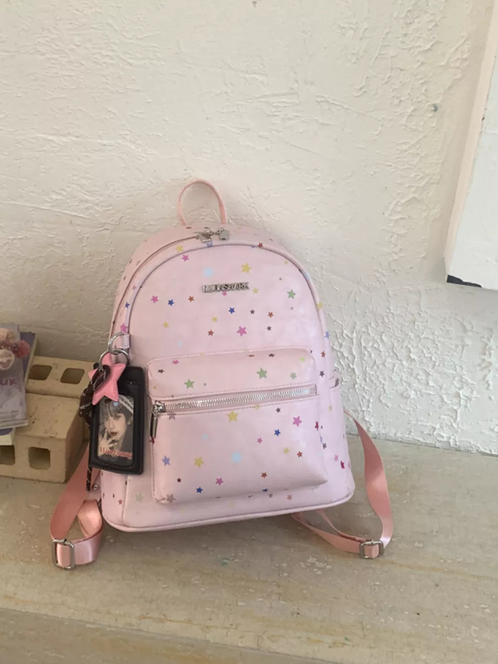 Blush pink mini backpack with colorful star print and a photo charm.