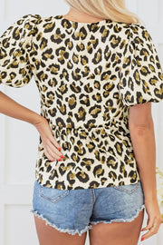 Leopard print peplum blouse with puff sleeves and cinched waist detail.