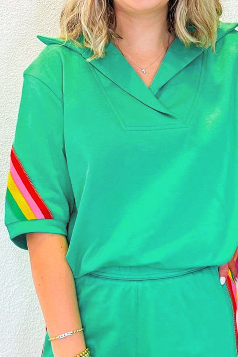 Green activewear shorts with rainbow stripe detail on sleeve