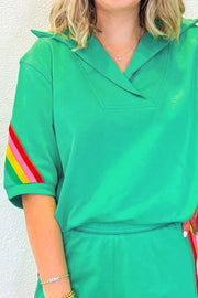 Green activewear shorts with rainbow stripe detail on sleeve